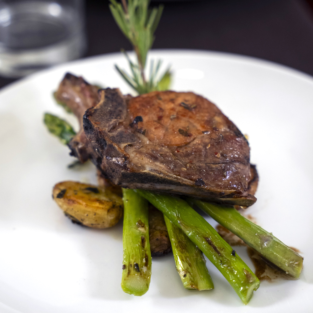 Steak on a bed of asparagus and roasted potatoes on a white plate