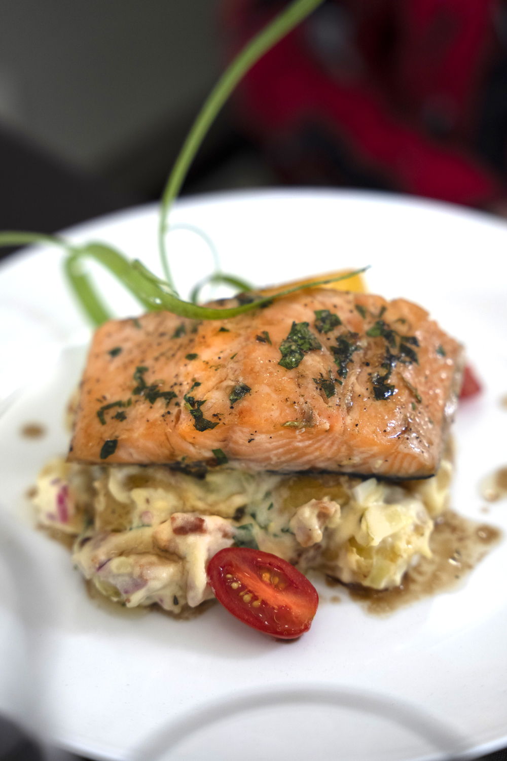 Dinner of grilled salmon on a bed of mashed potatoes and cherry tomatoes on a white plate