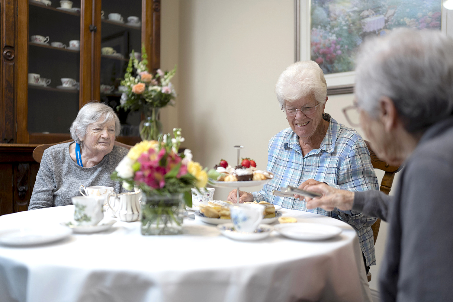 Residents enjoying afternoon tea with a tray of cakes and treats